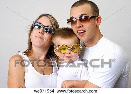 Smiling young family wears sunglasses for eye protection and fun. View Large Photo Image Picture - Smiling young family wears sunglasses for eye protection and fun.. Fotosearch