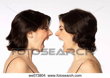 Picture - Twin sisters argue and scream at each other face to face. Fotosearch
