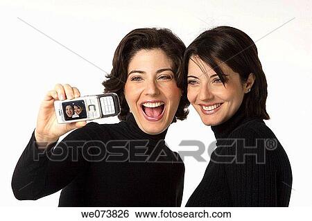Twin sisters having their picture taken with a cell phone View Large Photo Image Stock Photograph - Twin sisters having their picture taken with a cell phone. Fotosearch