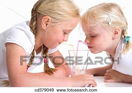 Two blond girls drinking lemonade with a straw View Large Photo Image Stock Photo - Two blond girls drinking lemonade with a straw. Fotosearch