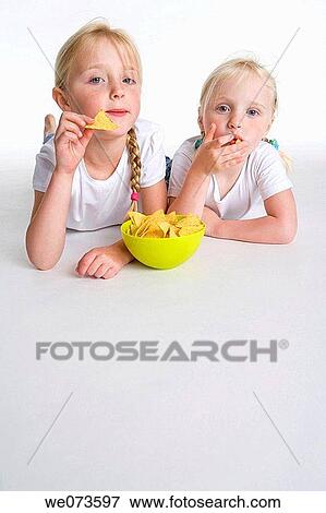 Stock Photo - Two blond girls eating chips. Fotosearch
