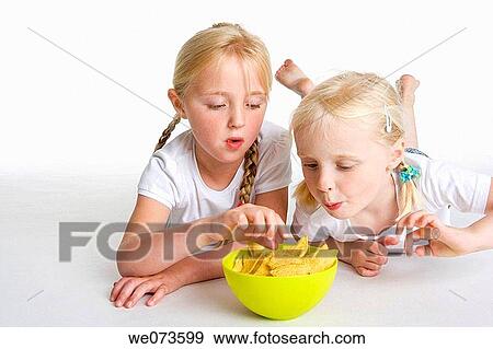 Two blond girls eating chips View Large Photo Image Stock Photo - Two blond girls eating chips. Fotosearch