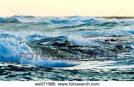 Stock Photograph - Waves churn amidst rough water of the Pacific Ocean off South Point on the big Island of Hawaii at dusk. Hawaii, USA. South Point is the southern most point of the USA.. Fotosearch
