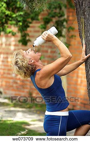Woman drinks water after exercise View Large Photo Image Stock Photo - Woman drinks water after exercise. Fotosearch