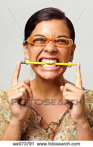 Stock Image - Woman in her 30s with retro sunglasses bites pencil. Fotosearch