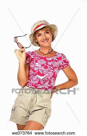 Woman in her 60s poses with sunglasses in a studio setting View Large Photo Image Picture - Woman in her 60s poses with sunglasses in a studio setting. Fotosearch