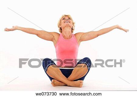Woman in her 60s stretches and raises her open arms towards the sky in a studio setting View Large Photo Image Stock Image - Woman in her 60s stretches and raises her open arms towards the sky in a studio setting. Fotosearch