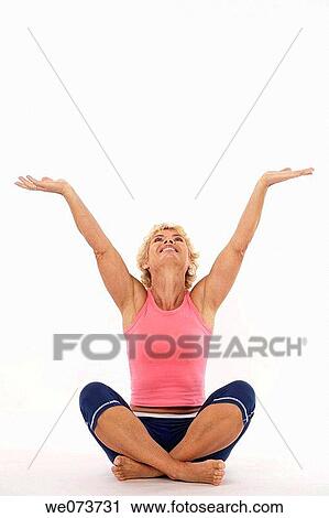 Woman in her 60s stretches and raises her open arms towards the sky in a studio setting View Large Photo Image Stock Image - Woman in her 60s stretches and raises her open arms towards the sky in a studio setting. Fotosearch