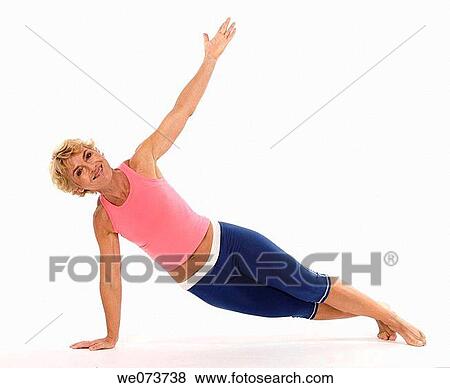 Stock Photo - Woman in her 60s stretches in a studio setting. Fotosearch