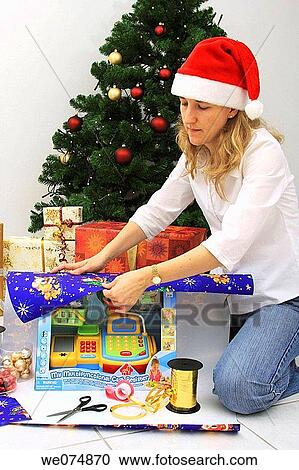 Woman wearing father Christmas hat, wrapping up Christmas present, Christmas gift View Large Photo Image Stock Image - Woman wearing father Christmas hat, wrapping up Christmas present, Christmas gift. Fotosearch