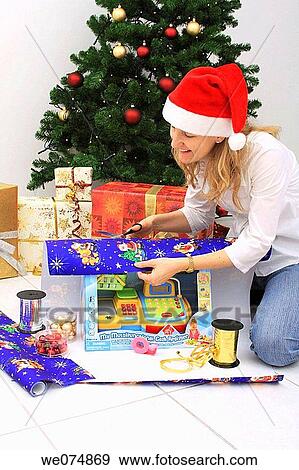 Woman wearing father Christmas hat, wrapping up Christmas present, Christmas gift View Large Photo Image Stock Photo - Woman wearing father Christmas hat, wrapping up Christmas present, Christmas gift. Fotosearch
