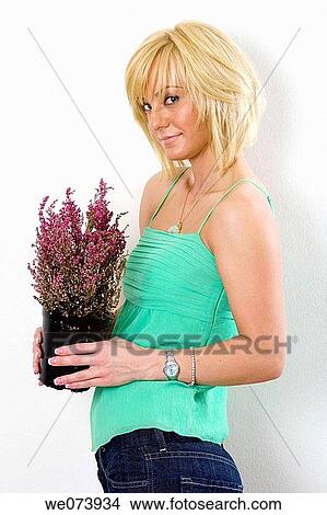 Young blond caucasian woman in her 20's holds a house plant inside a home in Southern California, USA View Large Photo Image Picture - Young blond caucasian woman in her 20's holds a house plant inside a home in Southern California, USA. Fotosearch