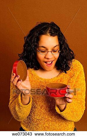 Young Spanish woman, wearing glasses, looking into a small red container. View Large Photo Image Stock Image - Young Spanish woman, wearing glasses, looking into a small red container.. Fotosearch