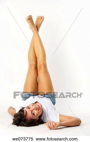 Young woman lies feet up in a studio setting View Large Photo Image Stock Photography - Young woman lies feet up in a studio setting. Fotosearch