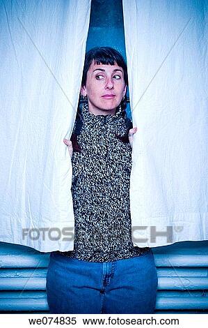 Young woman peeking out from behind a pair of curtains. View Large Photo Image Stock Photography - Young woman peeking out from behind a pair of curtains.. Fotosearch