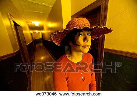 Young woman, wearing a wide hat, posing in the hallway of her apartment building. View Large Photo Image Stock Photograph - Young woman, wearing a wide hat, posing in the hallway of her apartment building.. Fotosearch