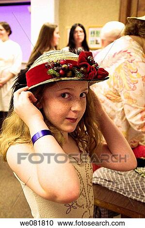 Stock Image - 11-year-old girl trying on 19th century hat at Monroe County historical museum, Indiana, USA. Fotosearch