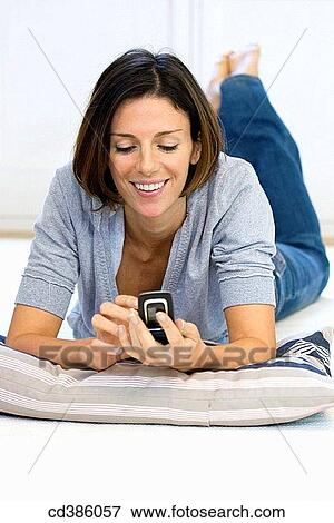 Stock Photo - barefoot, cell phone, brunette, at-home. Fotosearch