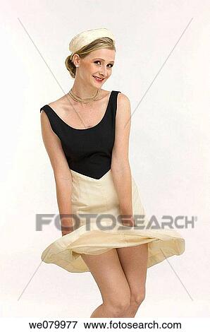 Stock Photo - Blond woman with lifted skirt posing in the Studio. Fotosearch