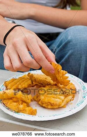 Close-up of a young woman's hand lifting a piece of fried food from a paper plate. View Large Photo Image Stock Photograph - Close-up of a young woman's hand lifting a piece of fried food from a paper plate.. Fotosearch