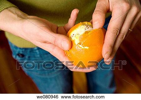 Stock Photograph - Close-up of a young woman's hands as she peels an orange.. Fotosearch