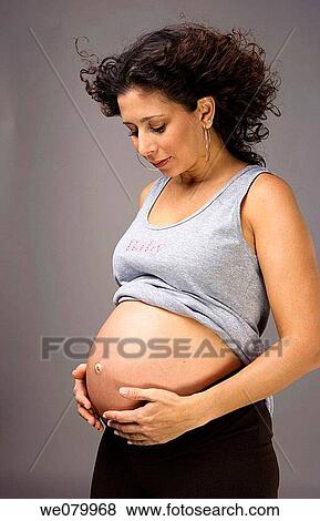 Latin pregnant woman posing in the studio looking at her belly View Large Photo Image Stock Photo - Latin pregnant woman posing in the studio looking at her belly. Fotosearch