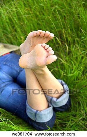Legs of a young barefooted woman resting on a peaceful field of grass View Large Photo Image Picture - Legs of a young barefooted woman resting on a peaceful field of grass. Fotosearch