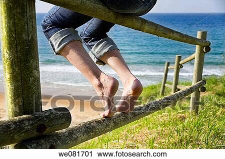 Legs of a young woman resting on a wooden fence near the beach View Large Photo Image Stock Image - Legs of a young woman resting on a wooden fence near the beach. Fotosearch
