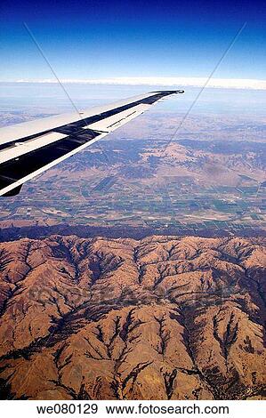Wing of jet plane over mostly-brown mountainous landscape View Large Photo Image Stock Photo - Wing of jet plane over mostly-brown mountainous landscape. Fotosearch