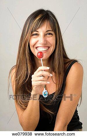 Woman in her late 30s posing in a studio setting with a lollypop View Large Photo Image Stock Photo - Woman in her late 30s posing in a studio setting with a lollypop. Fotosearch