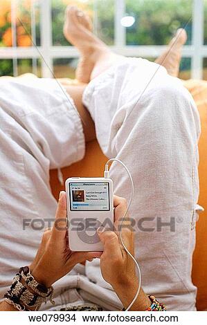Woman in her late 30s relaxing at home listening to music on her ipod View Large Photo Image Picture - Woman in her late 30s relaxing at home listening to music on her ipod. Fotosearch