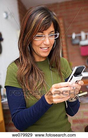 Woman in her late 30s writing text messages in a kitchen setting View Large Photo Image Stock Photo - Woman in her late 30s writing text messages in a kitchen setting. Fotosearch