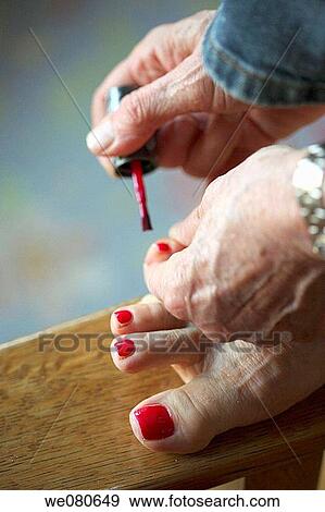Stock Photo - Woman painting toe nails red. Fotosearch