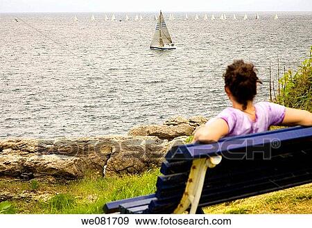 Woman siting on a bench watching the sailing boats View Large Photo Image Stock Photo - Woman siting on a bench watching the sailing boats. Fotosearch