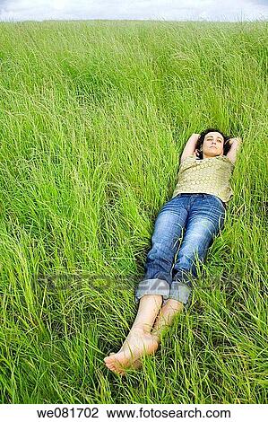 Young barefooted woman resting on a peaceful field of grass View Large Photo Image Stock Image - Young barefooted woman resting on a peaceful field of grass. Fotosearch