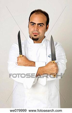 Young latin Chef holding two knives looking at the camera View Large Photo Image Stock Photo - Young latin Chef holding two knives looking at the camera. Fotosearch