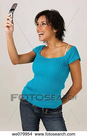 Picture - Young Latin model in her 20s taking a picture of herself with a cell phone. Fotosearch