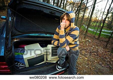 Young man sitting next to the open trunk of his car which contains two computer monitors View Large Photo Image Stock Photo - Young man sitting next to the open trunk of his car which contains two computer monitors. Fotosearch