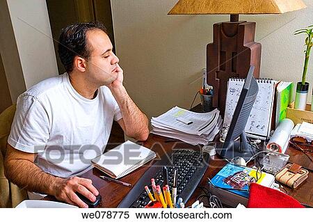 Young man working at his deak in his apartment. View Large Photo Image Stock Photography - Young man working at his deak in his apartment.. Fotosearch
