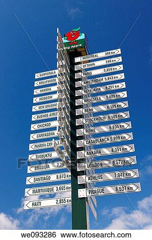 Stock Photograph - A big apple sign post of distances to world cities in Purdy Corners Colborne Ontario Cramahe Township. Fotosearch