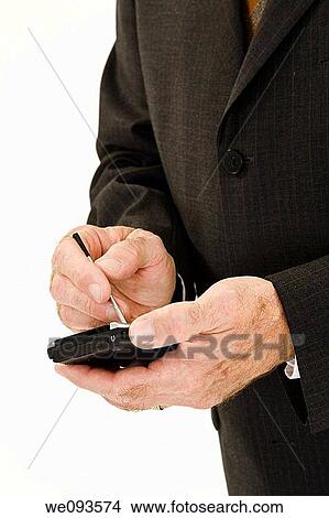 A caucasian businessman wearing a black business suit and white shirt He is shown on a white background working with a pda View Large Photo Image Picture - A caucasian businessman wearing a black business suit and white shirt He is shown on a white background working with a pda. Fotosearch