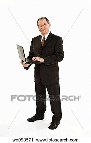 Stock Image - A caucasian businessman with a receding hairline wearing a black business suit and white shirt He is shown on a white background holding a laptop and is smiling. Fotosearch