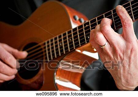 Stock Photograph - A close up view of musician's hands on his guitar. Fotosearch