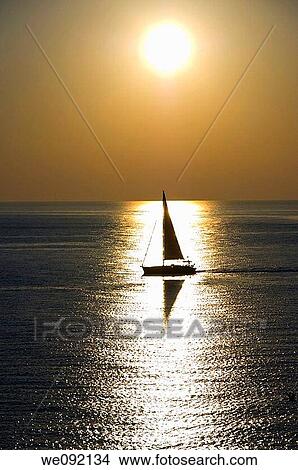 A sailboat navigating in the water with sunlight View Large Photo Image Picture - A sailboat navigating in the water with sunlight. Fotosearch