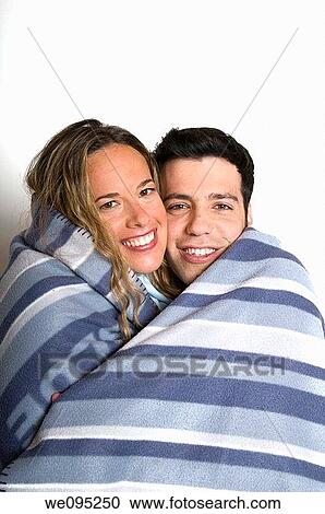 A young romantic couple in their 20s wrapped together in a blanket on a white background Model Releases available View Large Photo Image Stock Image - A young romantic couple in their 20s wrapped together in a blanket on a white background Model Releases available. Fotosearch