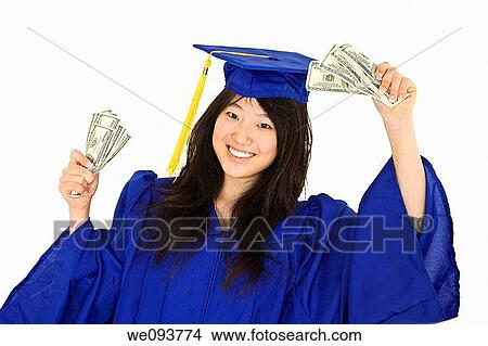 An Asian teenage in blue graduation gown and smiling while hold US money to illustrate to high cost of education She is on a white background View Large Photo Image Picture - An Asian teenage in blue graduation gown and smiling while hold US money to illustrate to high cost of education She is on a white background. Fotosearch
