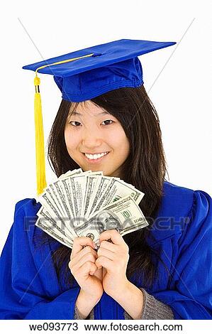 An Asian teenage in blue graduation gown and smiling while hold US money to illustrate to high cost of education She is on a white background View Large Photo Image Stock Image - An Asian teenage in blue graduation gown and smiling while hold US money to illustrate to high cost of education She is on a white background. Fotosearch