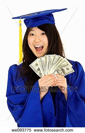 Stock Photography - An Asian teenage in blue graduation gown and smiling while hold US money to illustrate to high cost of education She is on a white background. Fotosearch
