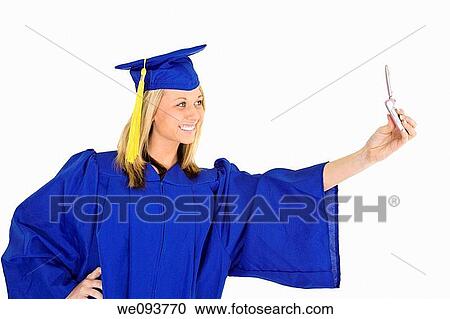 An Caucasian teenage in blue graduation gown and smiling while holding a cell phone and taking a picture of herself She is on a white background View Large Photo Image Stock Image - An Caucasian teenage in blue graduation gown and smiling while holding a cell phone and taking a picture of herself She is on a white background. Fotosearch