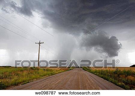 Angry looming cumulus thunder clouds releasing rain in a rural thunderstorm with dirt road leading into the distance View Large Photo Image Stock Photo - Angry looming cumulus thunder clouds releasing rain in a rural thunderstorm with dirt road leading into the distance. Fotosearch